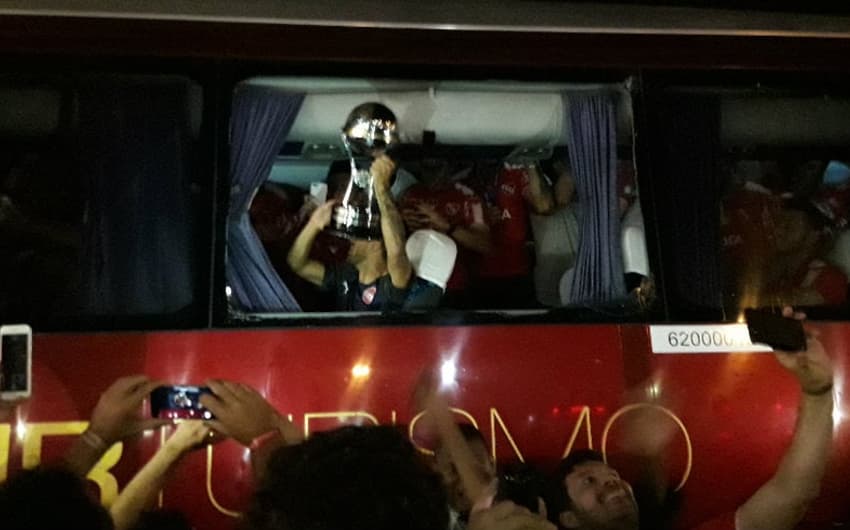 Jogadores do Independiente comemoram com a taça da Sul-Americana na janela do ônibus que foi quebrada (Foto: Igor Siqueira)