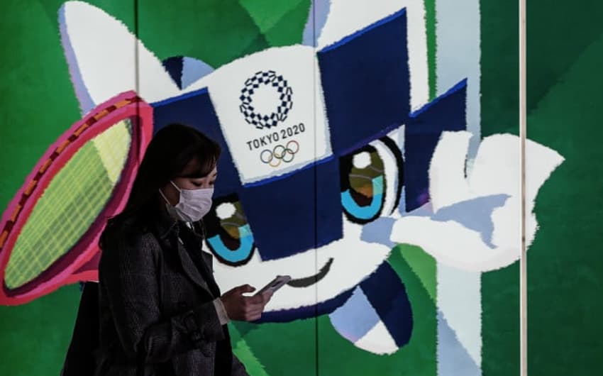 Japonesa em frente a uma arte dos Jogos Olímpicos em Tóquio (AFP)