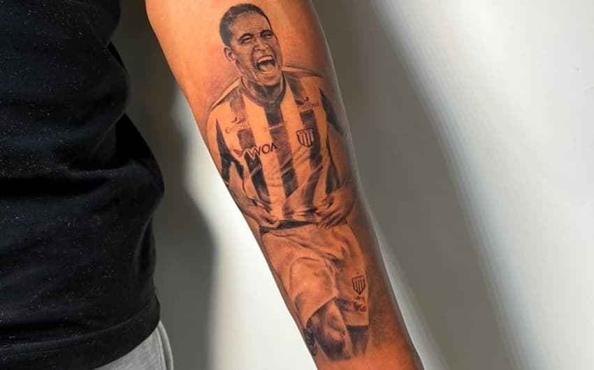 Tatuagem de Cléber Santana no braço do filho, Aroldo Neto