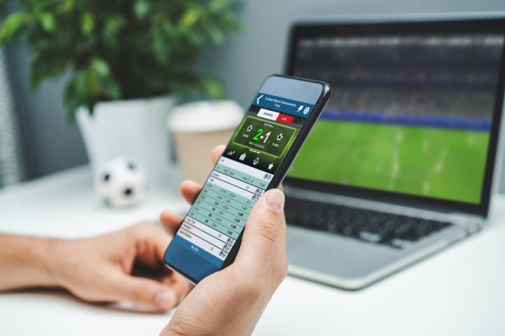 Close up cropped shot of male hands betting online using gambling mobile application on his phone