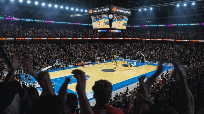 High Angle Establishing Wide Shot of a Whole Arena of Spectators Watching a Basketball Championship Game. Teams Play, Crowds of Fans Raise Hands and Cheer. Sports Channel Live Television Broadcast