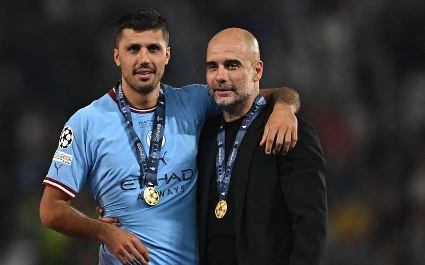 O meio-campista Rodri ao lado do treinador Pep Guardiola (Foto: Paul Ellis/AFP)