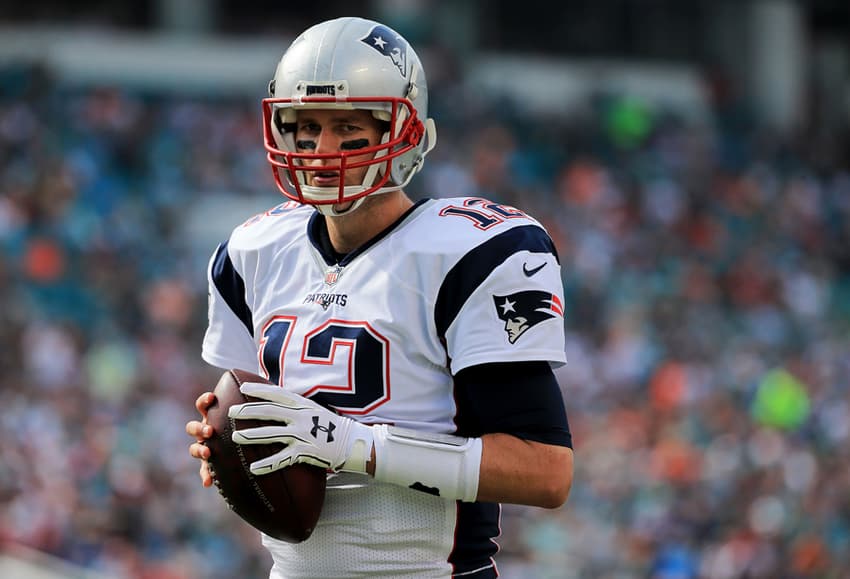 Tom Brady, quarterback do New England Patriots, segurando a bola do futebol americano