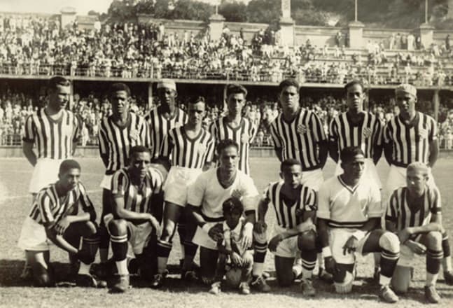 Dia histórico para o Bangu, antes da partida contra o Fluminense, nas Laranjeiras, em 12 de novembro de 1933. Em pé: Mário Carreiro, Ferro, Santana, Orlandinho, Plácido, Camarão, Médio da Guia e Tião. Agachados: Sobral, Ladislau, Euro (com a mascote Manô)