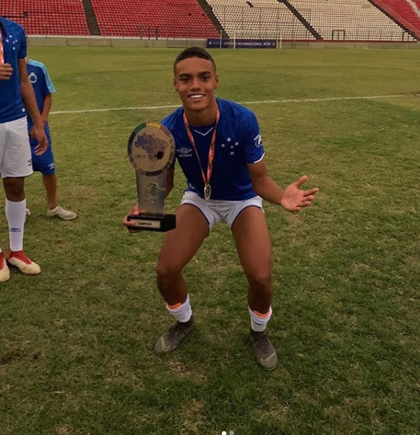 João ao lado do troféu fazendo mais uma vez o gesto do 