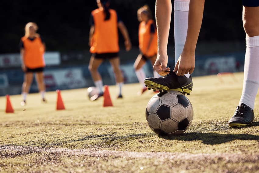 Close up of soccer player tying her shoelaces on playing field.