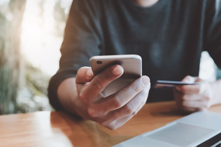 Online payment,Man’s hands holding smartphone and using credit card for online shopping.