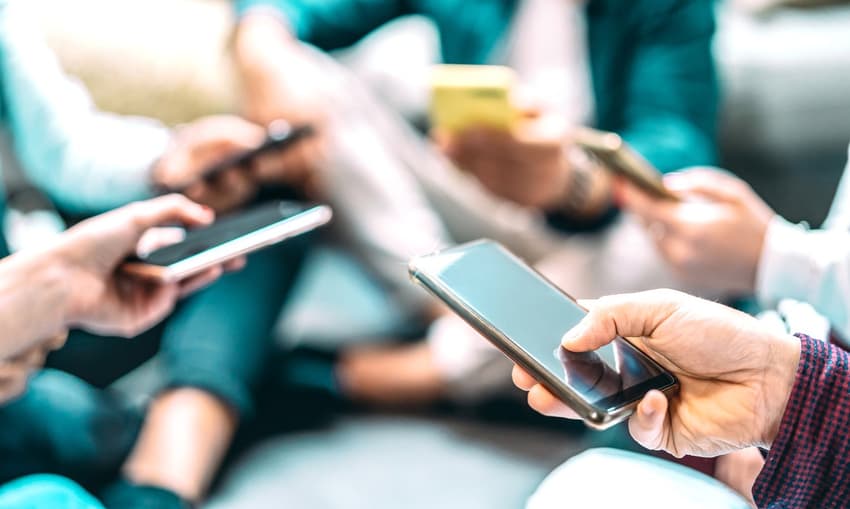 Close up of people using mobile smart phones – Detail of friends sharing photos on social media network with smartphone – Technology concept and cellphone culture with selective focus on right hand