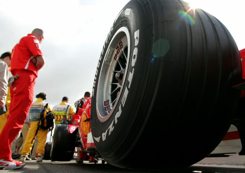 Mechanics wait near Ferrari with Bridgestone tyres during free practice session at French Grand Prix