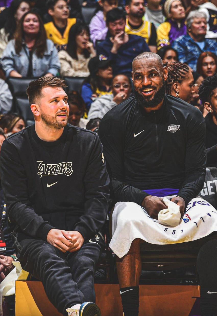 Lebron James e Luka Doncic sentados no banco de reserva dos Lakers (Foto: Reprodução/X)