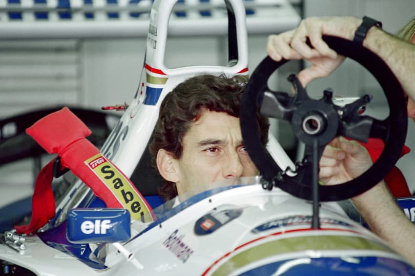 Brazilian F1 driver Ayrton Senna inspects and adjusts the steering wheel in the pits on May 1, 1994 before the start of the San Marino Grand Prix in Imola. Senna died after crashing in the seventh lap. AFP PHOTO JEAN-LOUP GAUTREAU
