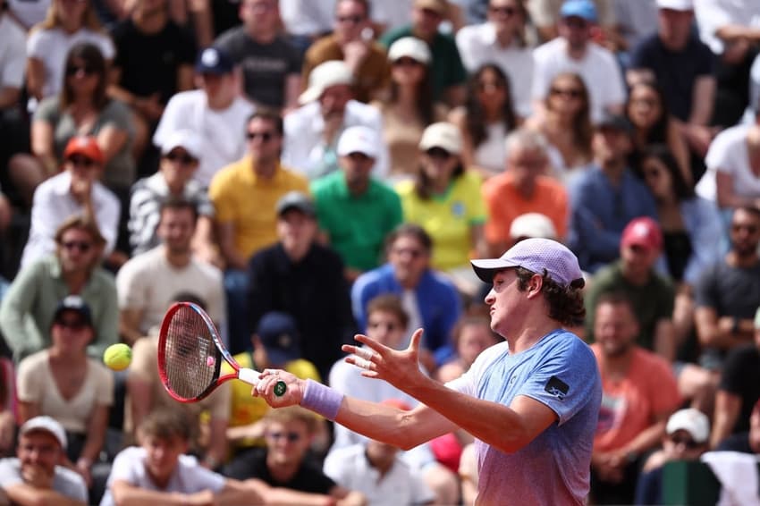 João Fonseca devolve a bola contra o francês Pierre-Hugues Herbert em Roland Garros (Foto: Anne-Christine POUJOULAT / AFP)