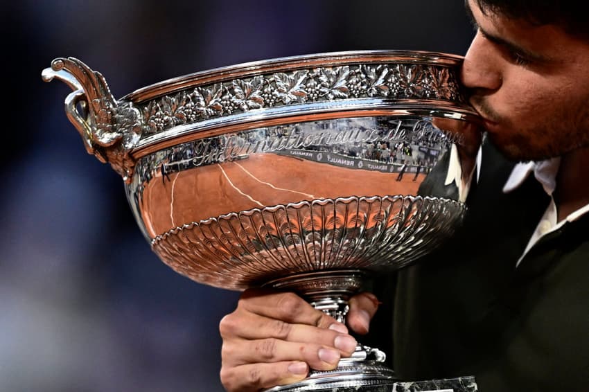 O espanhol Carlos Alcaraz beija o troféu de Roland Garros (Foto: JULIEN DE ROSA / AFP)