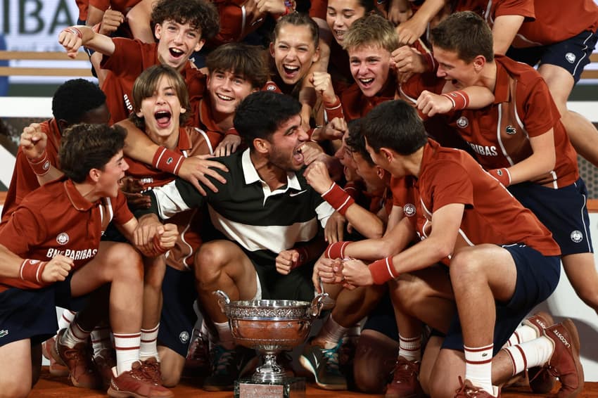 O espanhol Carlos Alcaraz comemora com os boleiros o segundo título de Roland Garros (Foto: Thibaud MORITZ / AFP)