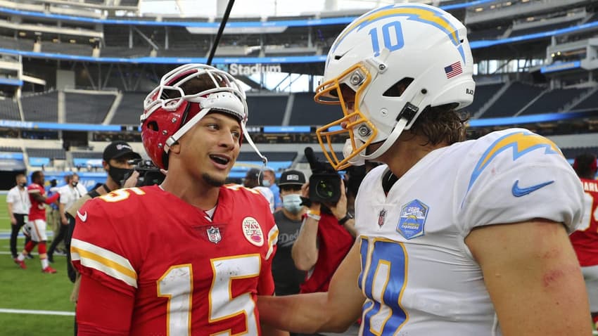 Patrick Mahomes dos Chiefs de vermelho olhando para Justin Herbert, dos Chargers, de branco e azul. Ambos Quarterbacks vão jogar na partida da NFl no Brasil