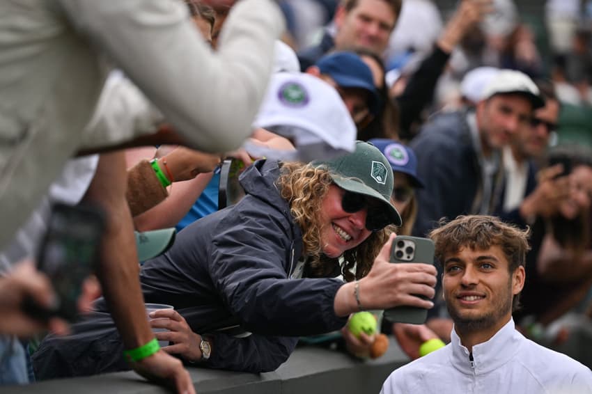 O italiano Flavio Cobolli posa para selfie com fã após derrotar o croata Marin Cilic em Wimbledon (Foto: Glyn KIRK / AFP) 