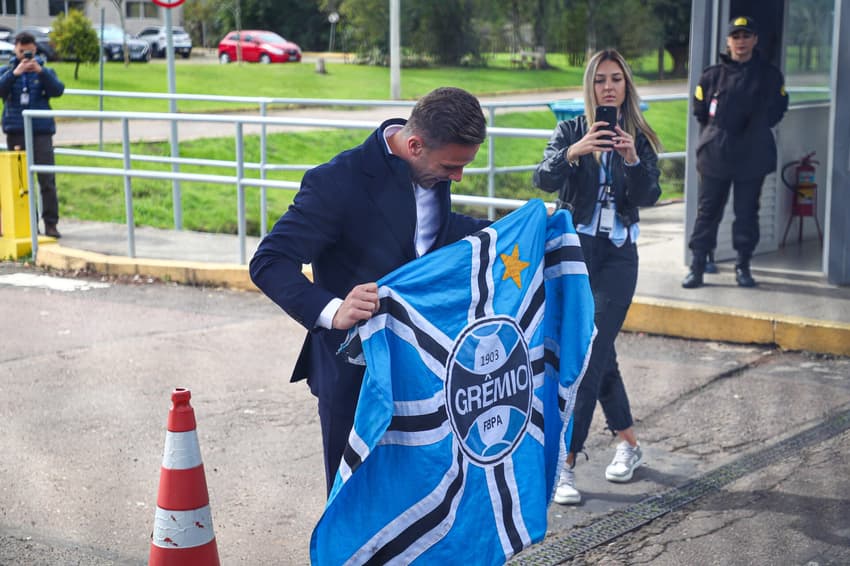 Arthur com bandeira do Grêmio após desembarcar no Aeroporto Salgado Filho. (Foto: Angelo Pieretti/Grêmio FBPA)
