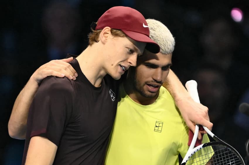 Italiano Jannik Sinner é abraçado pelo espanhol Carlos Alcaraz após a vitória na decisão do ATP Finals de Turim (Photo by Marco BERTORELLO / AFP)