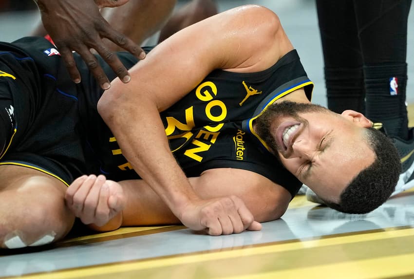 Stephen Curry deitado com dores em jogo entre Warriors e Rockets na NBA (Foto: Thearon W. Henderson/Getty Images/AFP)