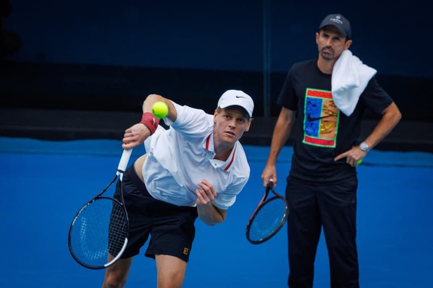 Observado pelo técnico Simone Vagnozzi, Jannik Sinner treina saque no Australian Open (Foto: Patrick HAMILTON / AFP)