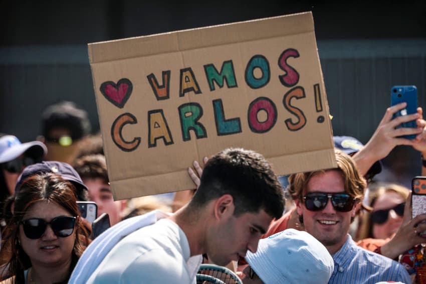 Torcedores do espanhol Carlos Alcaraz seguram cartazes antes de treino em Melbourne em 15 de janeiro de 2026, antes do Aberto da Austrália, que começa no dia 18. (Foto: David Gray/AFP)
