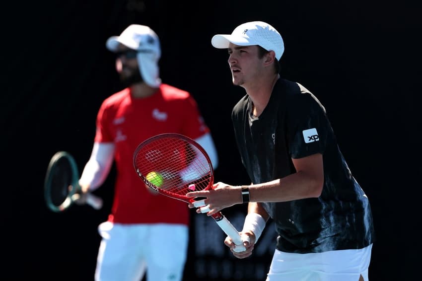 João Fonseca, sob os olhares do técnico Guilherme Teixeira, durante treino no Australian Open (Foto: Martin KEEP / AFP)