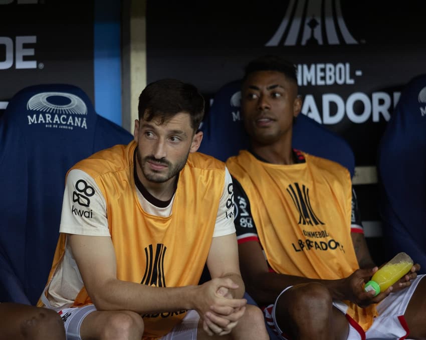 Viña e Bruno Henrique sentados no banco de reservas em jogo da Libertadores (Foto: Matheus Sanches / MyPhoto Press / Gazeta Press)