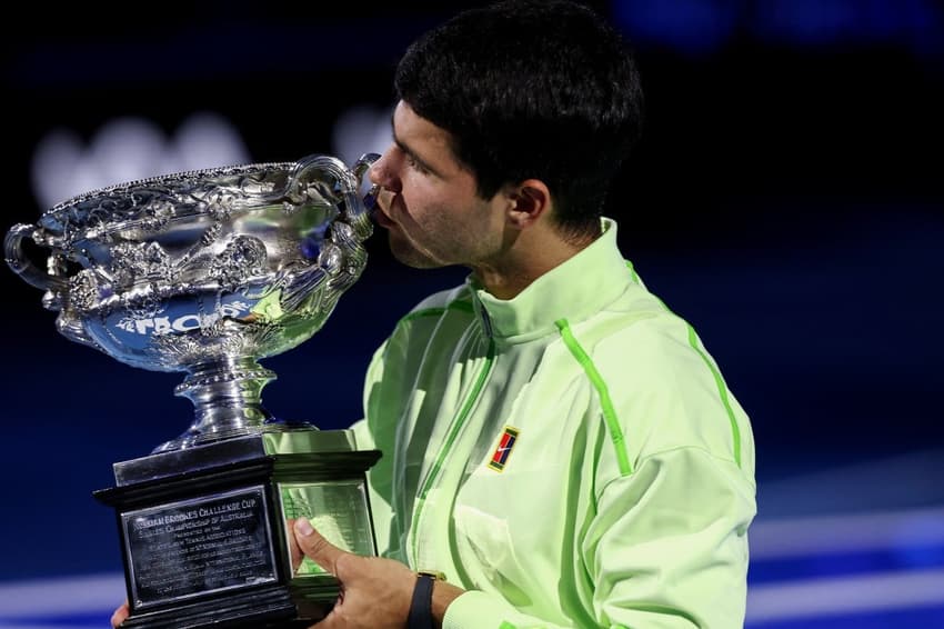O espanhol Carlos Alcaraz beija seu sétimo Grand Slam, o primeiro no Australian Open (Foto: IZHAR KHAN / AFP)
