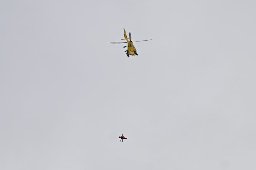 Socorristas chegam de helicóptero para resgatar a americana Lindsey Vonn após queda na prova de descida feminina dos Jogos Olímpicos de Inverno Milano-Cortina 2026, em Cortina d'Ampezzo, em 8 de fevereiro de 2026 (Foto:Tiziana FABI/AFP).