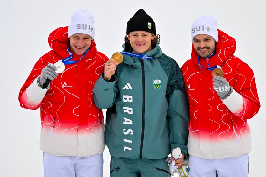 Da esquerda para a direita, Marco Odermatt (prata), Lucas Pinheiro Braathen (ouro) e Loic Meillard (bronze) celebram no pódio do slalom gigante masculino em 2026. (Foto: Fabrice Coffrini/AFP)