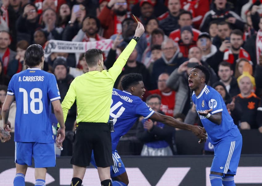 Árbitro francês Francois Letexier mostra cartão amarelo a Vini Jr ao comemorar gol do Real Madrid contra Benfica (Foto: Filipe Amorim/AFP)