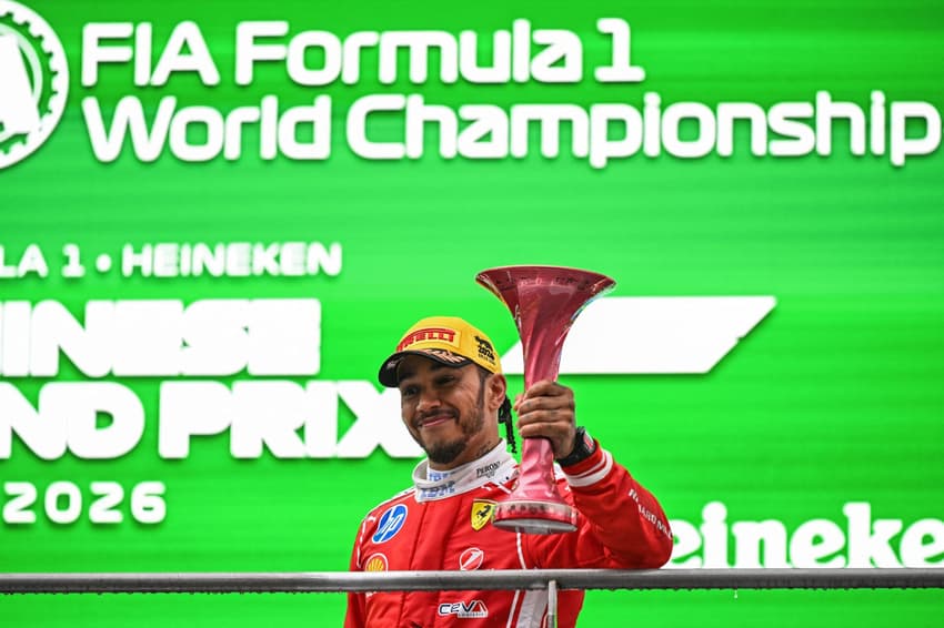 Lewis Hamilton celebra no pódio após terminar em terceiro lugar no GP da China de Fórmula 1, em 15 de março de 2026. (Foto: Greg Baker/AFP)