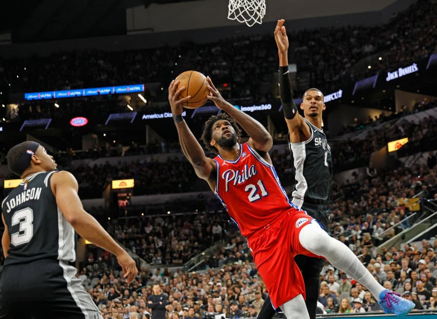 Joel Embiid, do Philadelphia 76ers, avança sobre Victor Wembanyama, do San Antonio Spurs, no Frost Bank Center. (Foto: Ronald Cortes/Getty Images/AFP)