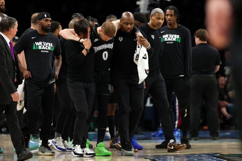 Donte DiVincenzo, do Timberwolves, é ajudado a levantar após aparente lesão no jogo quatro da primeira rodada dos playoffs da Conferência Oeste contra o Nuggets (Foto: David berding/Getty images/Afp)