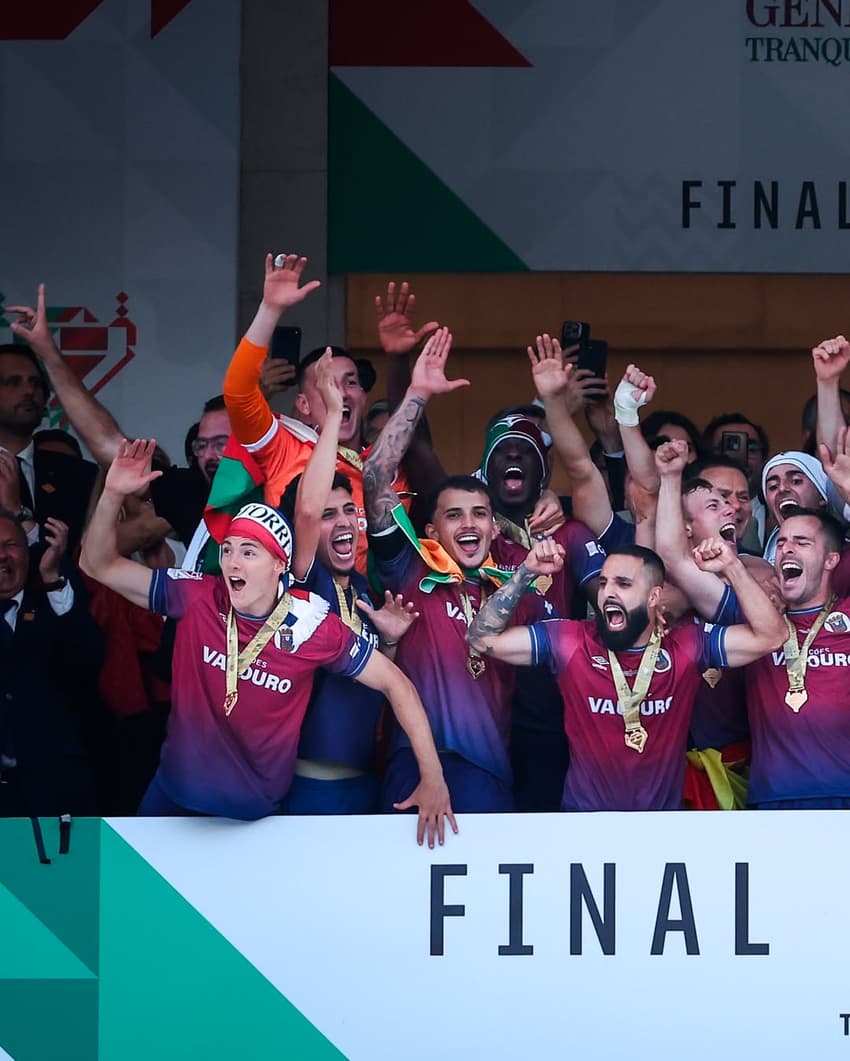 Jogadores do Torreense agrupados, utilizando o cordão da medalha do título no pescoço, com os braços erguidos para o ar comemorando o título.
