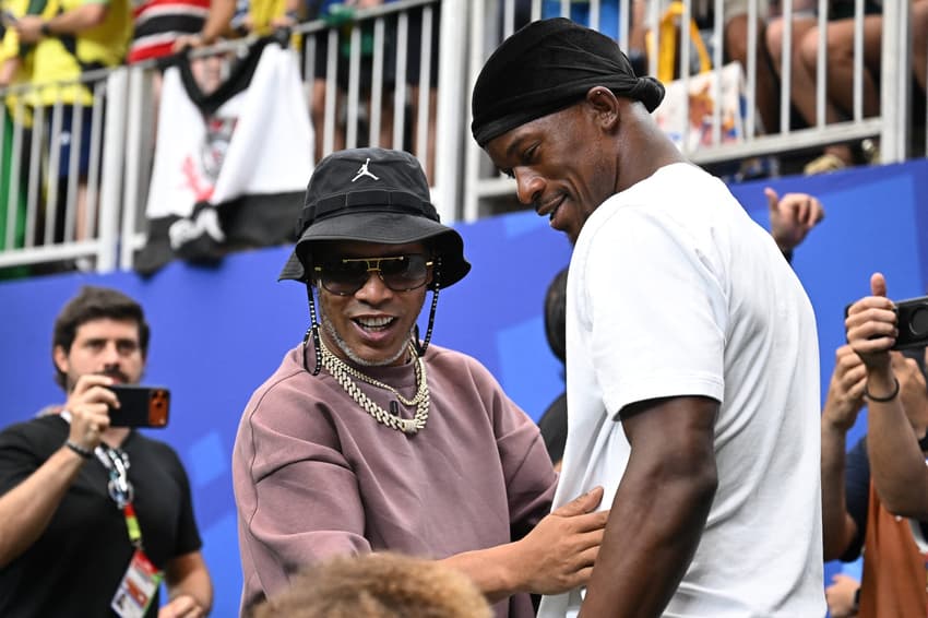 O ex-jogador de futebol brasileiro Ronaldinho (à esquerda) e o jogador de basquete norte-americano Jimmy Butler reagem antes da partida de futebol das oitavas de final da Copa do Mundo de 2026 entre Brasil e Japão, no Houston Stadium, em Houston
