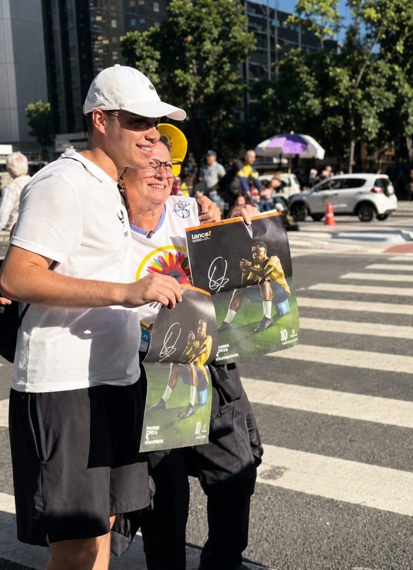 Casal de boné mostrando a parte autografada de Pelé do Manual do Torcedor do Lance!