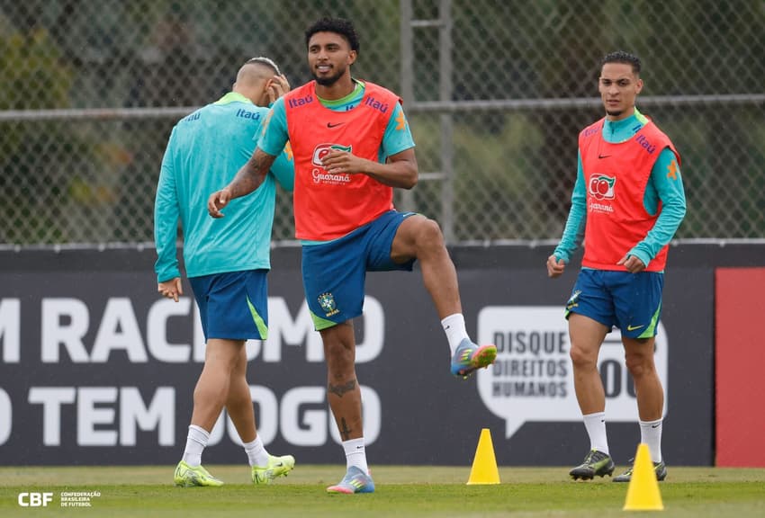 o volante Éderson se aquecendo com o colete laranja e uniforme verde de treino da seleção brasileira