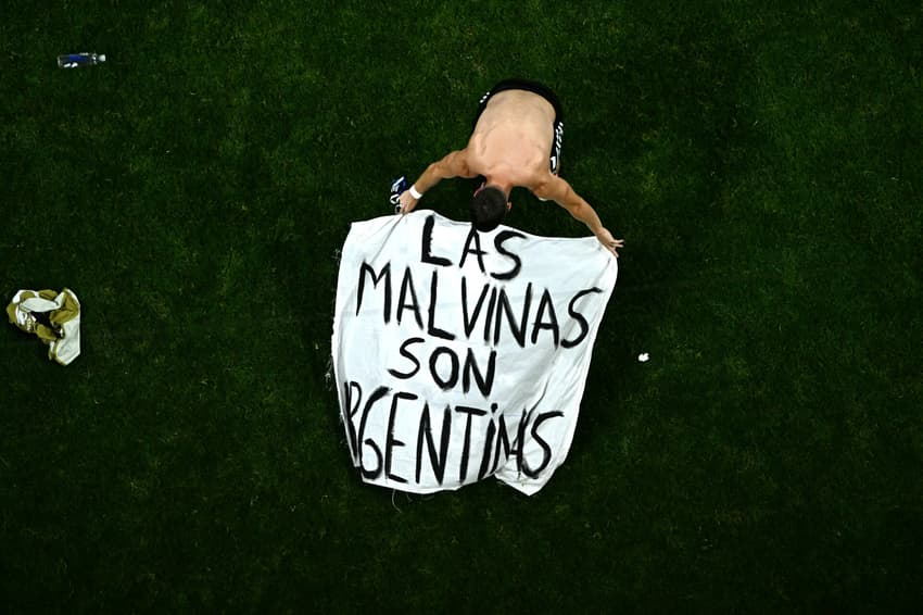 Giovani Lo Celso ajustando a bandeira com os dizeres: "As Malvinas são Argentinas".
