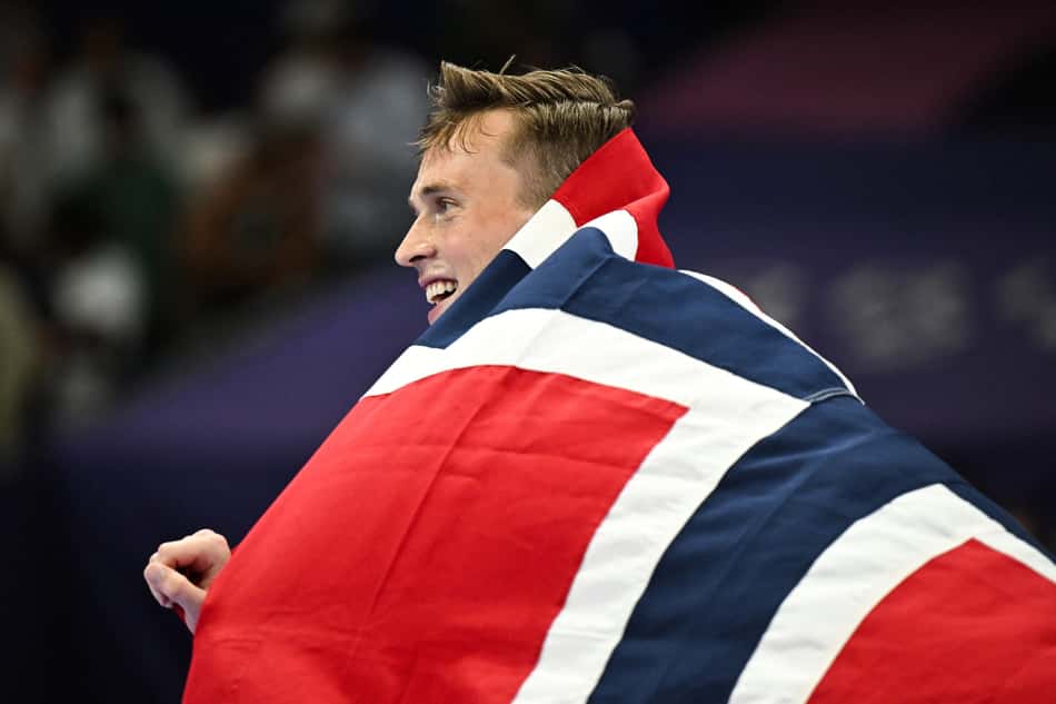 Karsten Warholm enrolado na bandeira da Noruega (Photo by Ben STANSALL / AFP)
