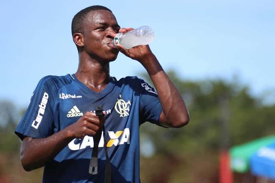 Vinicius Júnior acaba de ser vendido ao Real Madrid por nada menos do que 45 milhões de euros. Com apenas 16 anos, o atacante participou de apenas dois jogos pela equipe profissional do Rubro Negro, mas já chamava a atenção pela multa milionária antes mesmo de deixar a base. Com a venda, o Flamengo só fica atrás do Santos, pela venda de Neymar<br>