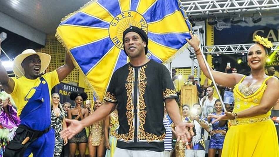 Paixões nacionais, o futebol e o samba caminham juntos na época do Carnaval no Brasil. Em 2019, Ronaldinho Gaúcho vai desfilar na Marquês de Sapucaí, no Rio de Janeiro, pela Unidos da Tijuca. O craque dos gramados esbanjou animação nos ensaios e faz parte de uma lista de atletas que têm uma ligação especial com a folia de Momo. 