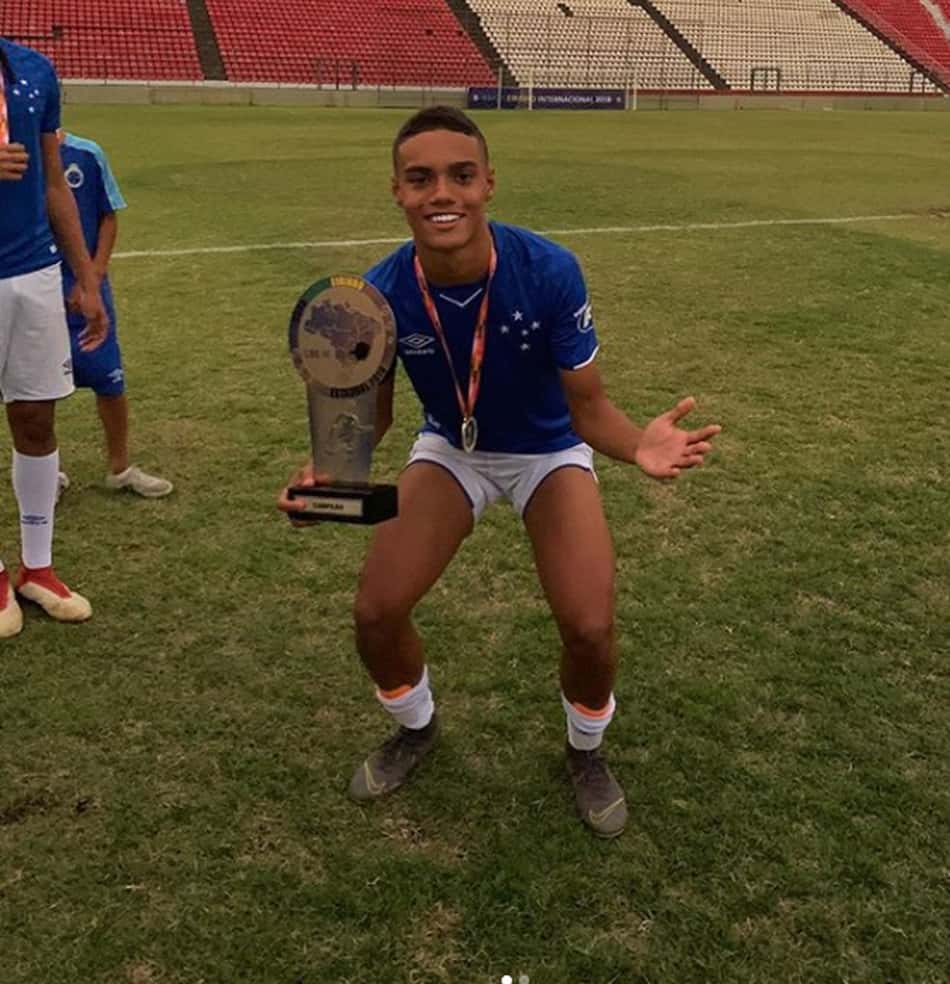 João ao lado do troféu fazendo mais uma vez o gesto do