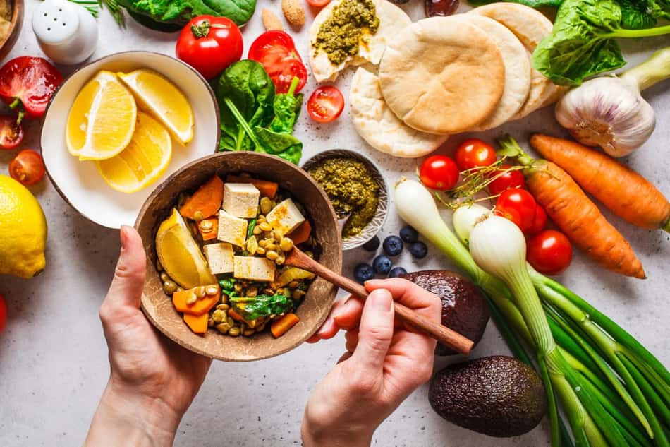 frutas, legumes e vegetais como cenoura, tomate e aipo sobre uma mesa branca.