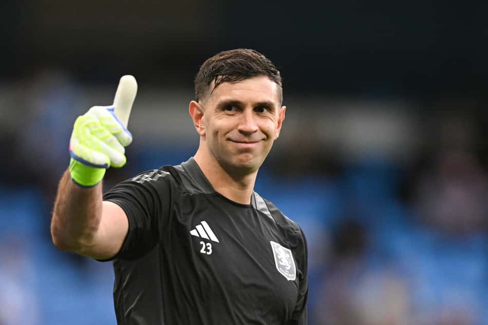 Argentina: Emiliano Martínez acena durante o aquecimento antes da partida entre Manchester City x Aston Villa (Foto: Oli Scarff/AFP)