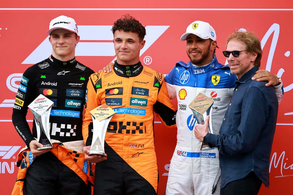 MIAMI, FLORIDA - MAY 03: Sprint winner Lando Norris of Great Britain and McLaren Second placed Oscar Piastri of Australia and McLaren Third placed Lewis Hamilton of Great Britain and Scuderia Ferrari and Jerry Bruckheimer, producer of the upcoming Formula One based movie, F1, during the Sprint ahead of the F1 Grand Prix of Miami at Miami International Autodrome on May 03, 2025 in Miami, Florida. Hector Vivas/Getty Images/AFP (Photo by Hector Vivas / GETTY IMAGES NORTH AMERICA / Getty Images via AFP)