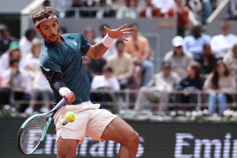 O italiano Lorenzo Musetti devolve a bola na partida contra o belga Yannick Hanfmann em Roland Garros (Foto: ALAIN JOCARD / AFP)