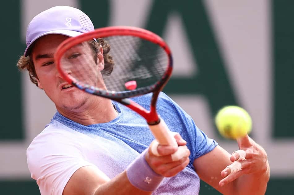 João Fonseca bate de direita na partida contra o francês Pierre-Hugues Herbert em Roland Garros (Photo by Anne-Christine POUJOULAT / AFP)