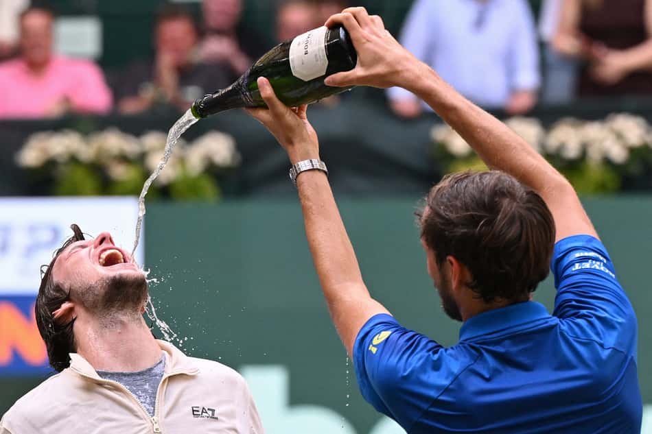 Alexander Bublik comemora o título de Halle bebendo champanhe do russo Daniil Medvedev (Foto: CARMEN JASPERSEN / AFP)