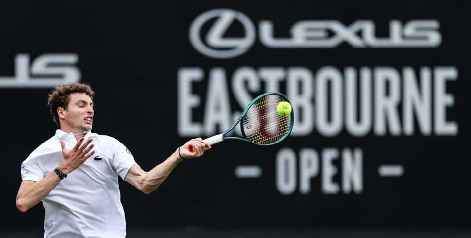 O francês Ugo Humbert devolve a bola contra o italiano Lorenzo Sonego em Eastbourne (Foto: Adrian Dennis / AFP)